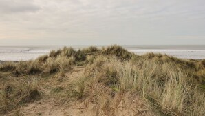 A beach with sand dunes and a cloudy sky. - Mcauliffe Lodge (Borth)
