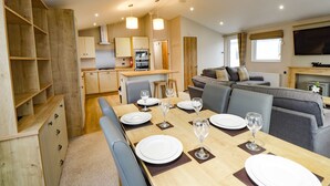 Een moderne, goed verlichte kamer met een eettafel voor vier personen, een bank en een keuken met kasten en apparatuur.