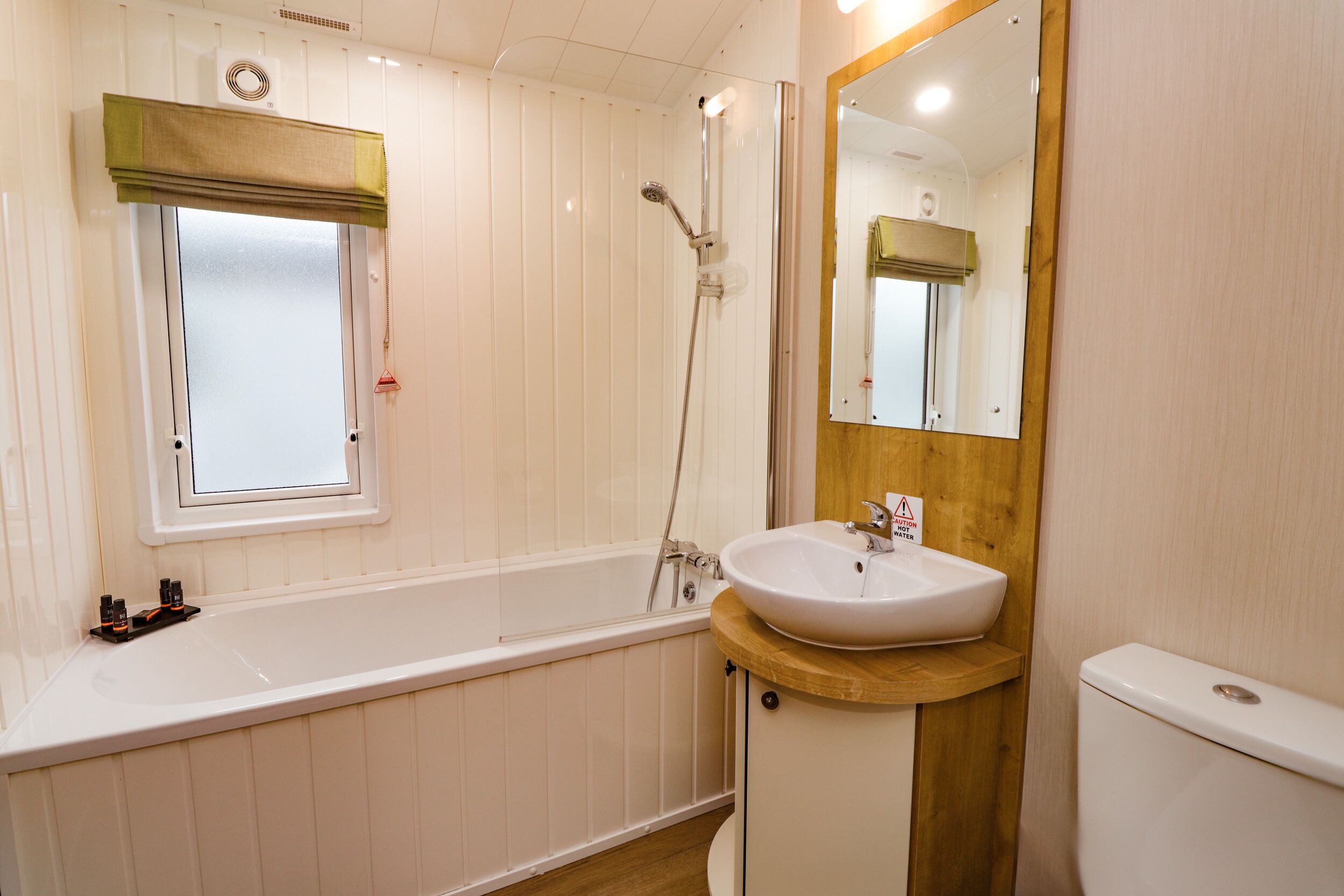 A bathroom with a bathtub, a sink, a mirror, and a toilet.