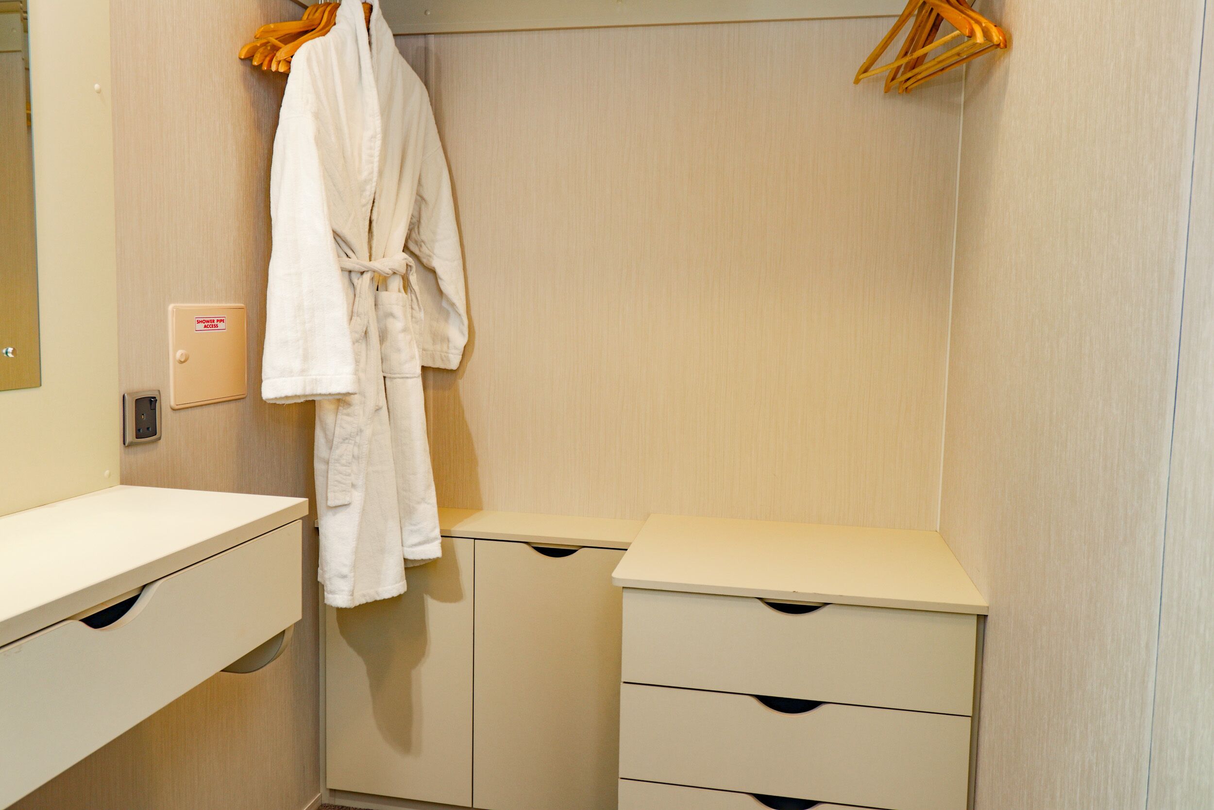 A bathroom with a white sink, mirror, and a robe hanging on a rack.