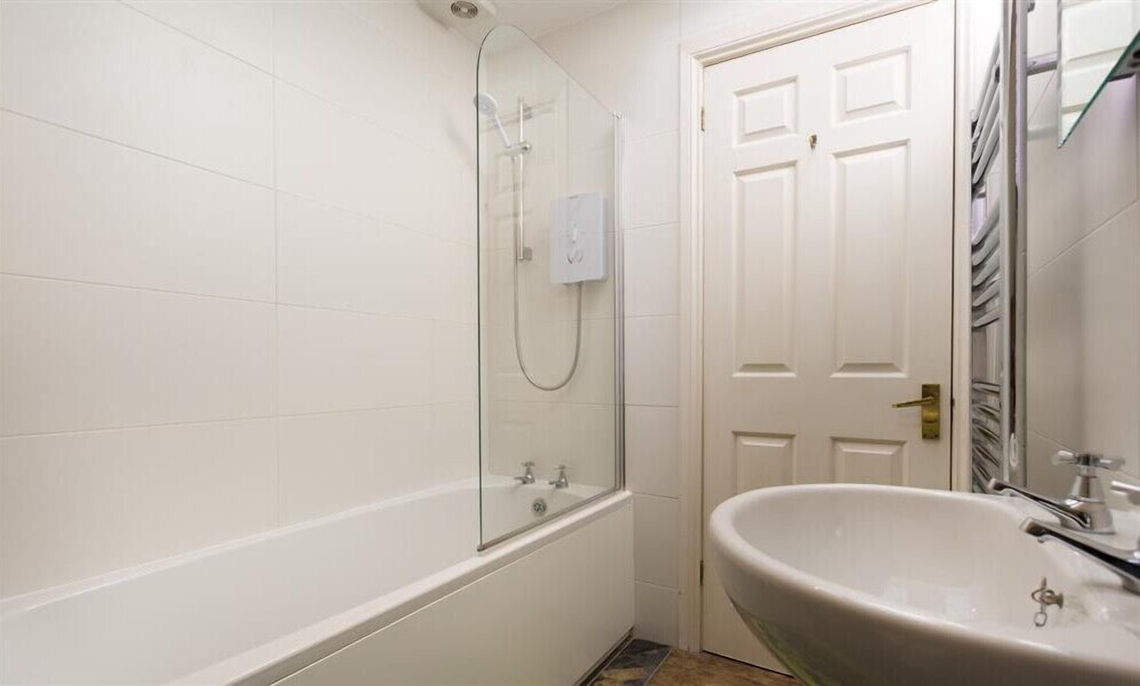 A bathroom with a glass-enclosed shower, a white bathtub, and a sink with a mirror.