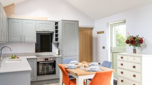Une cuisine moderne avec des meubles de couleur grise, une table à manger en bois et des chaises orange.