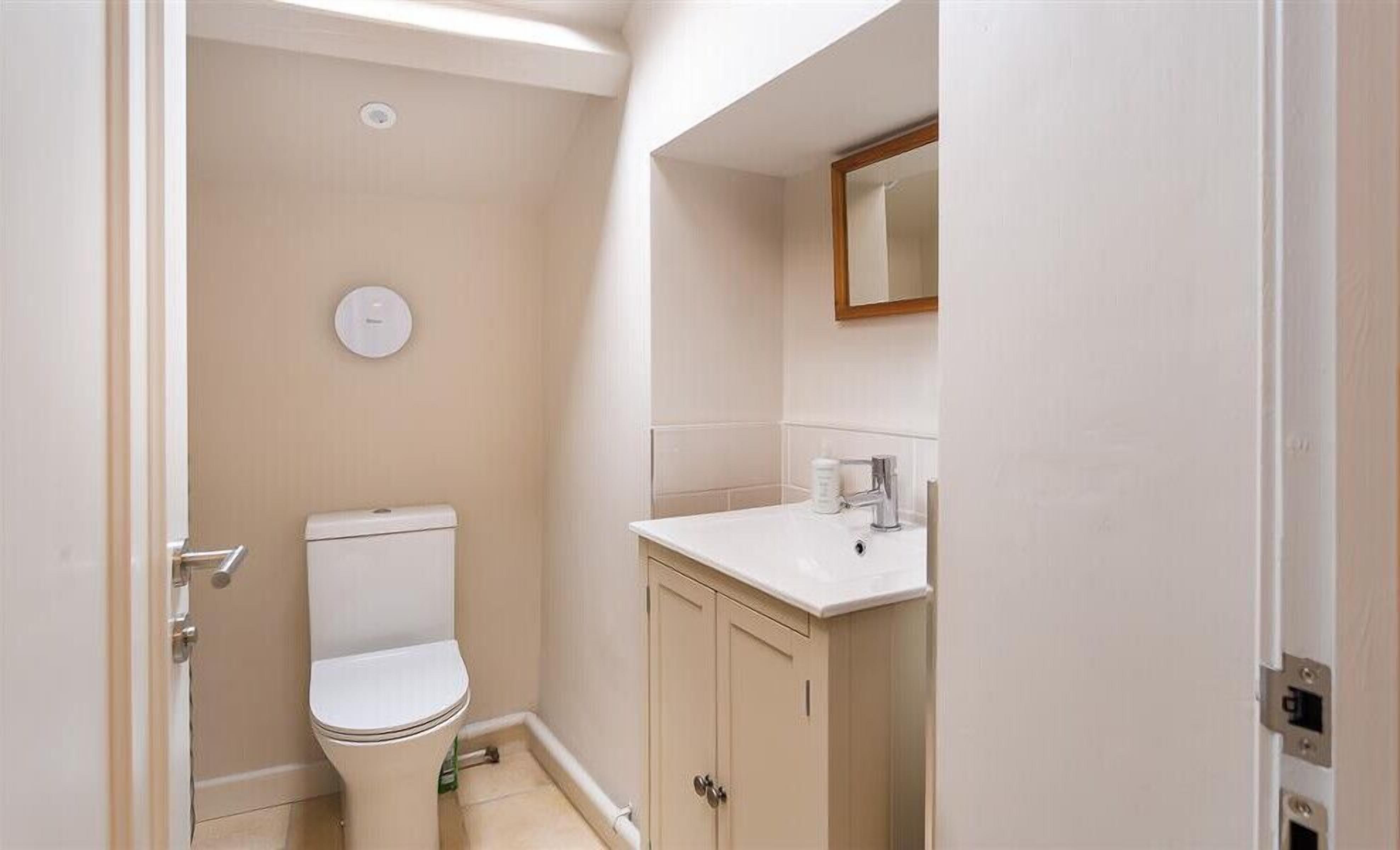 Une petite salle de bain propre, équipée de toilettes, d’un lavabo et d’un meuble de rangement.