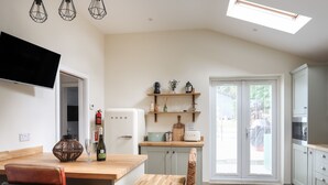 Une cuisine moderne avec une table en bois, une chaise en osier, un réfrigérateur blanc et un four encastré.