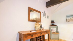 Une console en bois, agrémentée d’un miroir, d’un vase et d’un panneau d’affichage noir.
