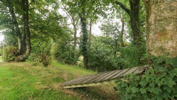 Eine Holzterrasse mit geneigtem Dach, umgeben von üppigem Grün und Bäumen.