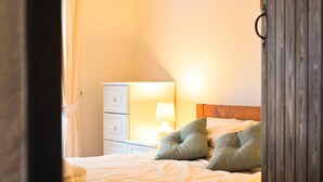 A bedroom with a bed, pillows, a nightstand, and a lamp. - Mosslea (Windermere)