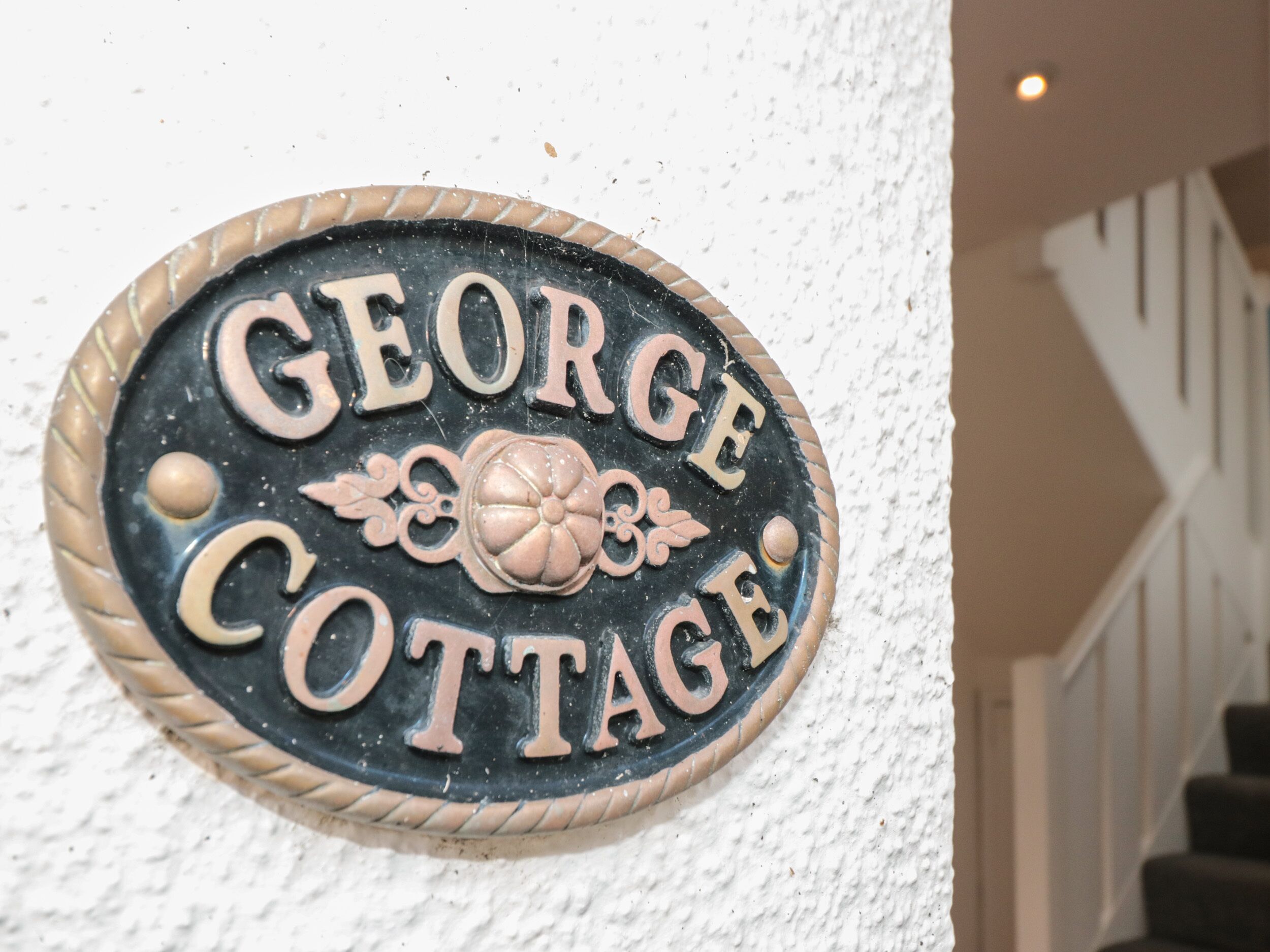 Ein Schild mit dem Schriftzug „GEORGE COTTAGE“ an einer Wand befestigt.