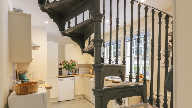 A kitchen with a staircase, a refrigerator, and a sink. - Maisie's Cottage (Dunblane)