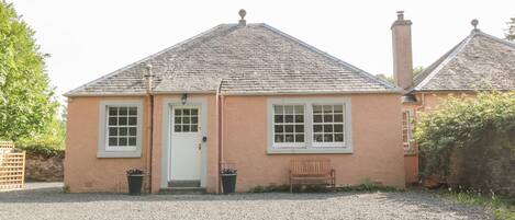 A single-story house with a white door, two windows, and a chimney.