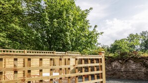 A wooden fence with a grid pattern, behind which are wicker chairs and a stone wall. - Maisie's Cottage (Dunblane)