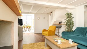 A modern living room with a wooden coffee table, a yellow armchair, a teal sofa, and a small plant.