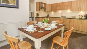 A dining area with a wooden table set for four, surrounded by wooden chairs. A white radiator is visible on the left, and a framed picture hangs on the wall. - Lansdowne Lodge (Market Rasen)