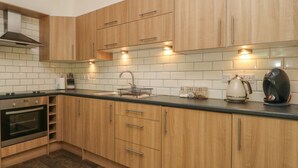 A modern kitchen with wooden cabinets, a stainless steel sink, and a built-in oven. - Lansdowne Lodge (Market Rasen)