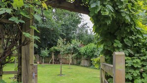 A wooden pergola with climbing plants, a grassy backyard, and a wooden fence. - Lansdowne Lodge (Market Rasen)
