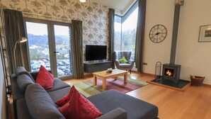 Un salon moderne avec un canapé, un téléviseur, une cheminée et une vue sur l’extérieur.
