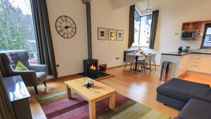 Un salon moderne avec une cheminée, un coin repas et une cuisine.