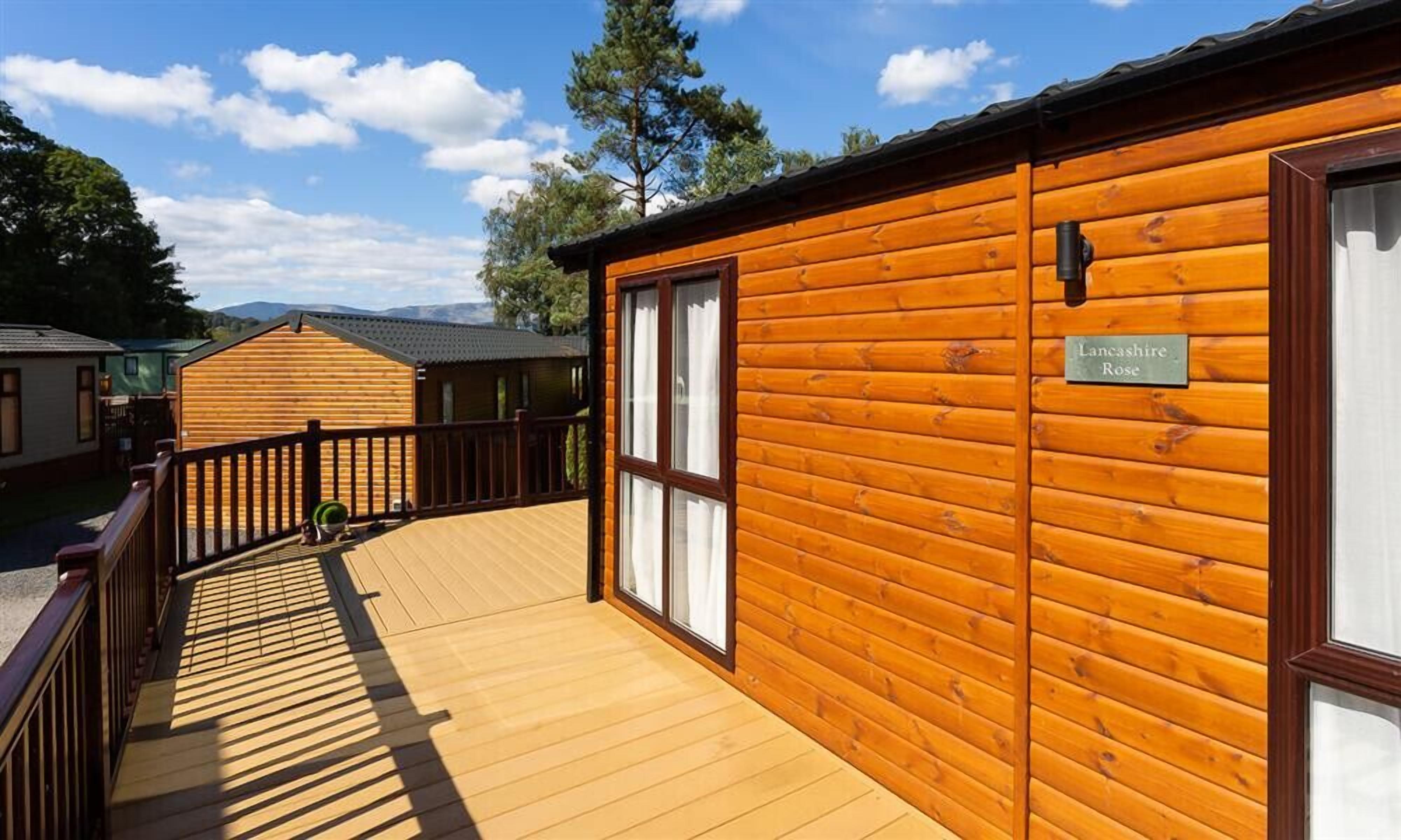 Une cabane en bois dotée d’une terrasse, d’une plaque portant l’inscription « Lancashire Rose », et offrant une vue sur les environs.
