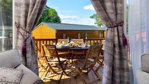 An outdoor dining area with a wooden table and chairs, a wooden fence, and a building in the background. - Lancashire Rose (Windermere)