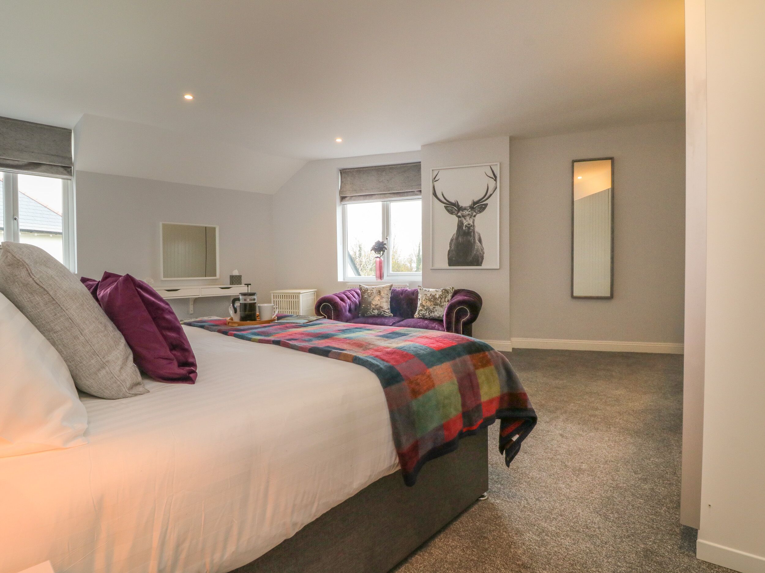 A bedroom with a bed, a dresser, a window, and a mirror.