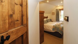 Un dormitorio con un armario de madera, una cama con colcha y una ventana con cortinas.