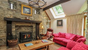 Un salón acogedor con chimenea de piedra, una mesa de centro de madera, un sofá rojo y un sillón de cuero.