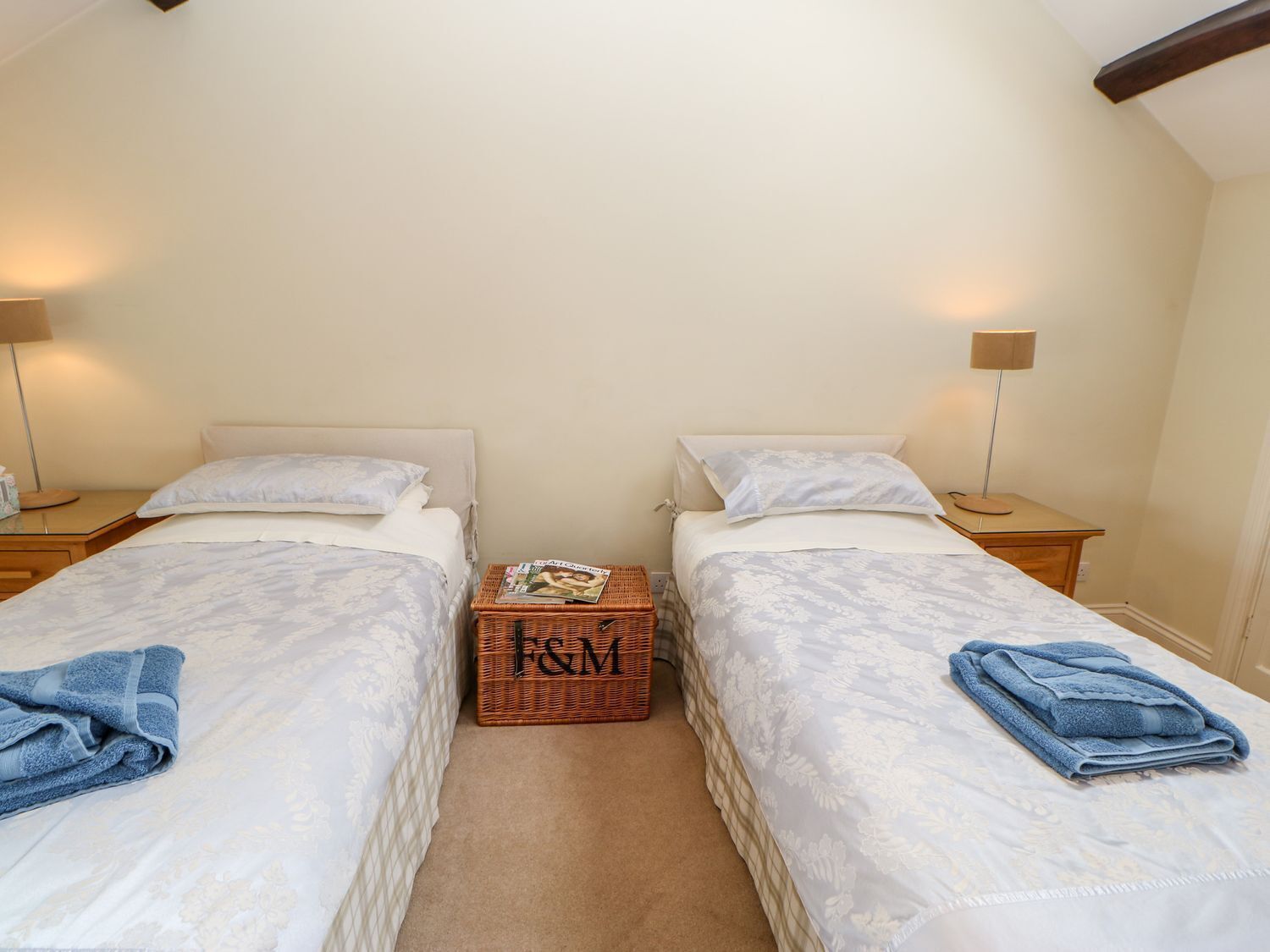 A twin room with two beds, each with a matching headboard, a small wooden chest of drawers, and bedside lamps.