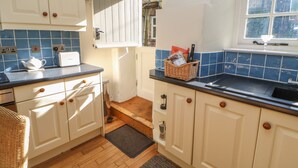 A kitchen with white cabinets, a blue tiled backsplash, a sink, and a window with a view. - Demonicus (Leyburn)