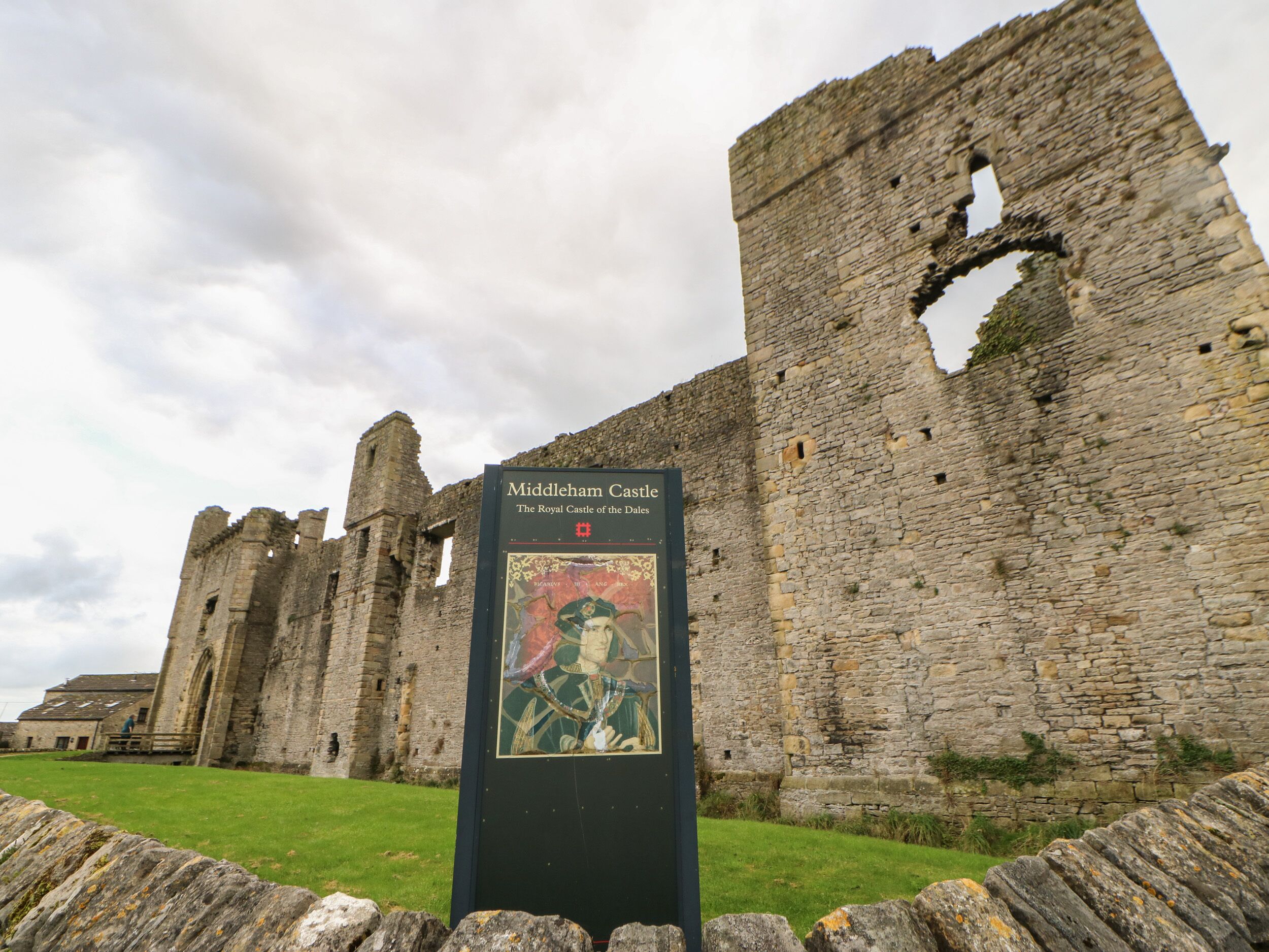 Les ruines du château de Middleham, avec un panneau d’information historique.