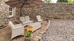 A stone wall, wicker furniture, and a potted plant. - Durham Bridge Barn (Kendal)