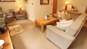 A living room with a sofa, armchairs, a wooden coffee table, a lamp, and a mirror. - Durham Bridge Barn (Kendal)