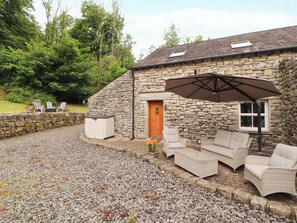 A stone building with a patio area, outdoor furniture, and a door.