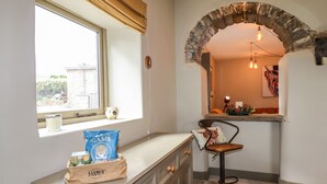 Una cucina con una finestra, un arco in pietra, uno sgabello da bar e un sacco di prodotti Farmer's.