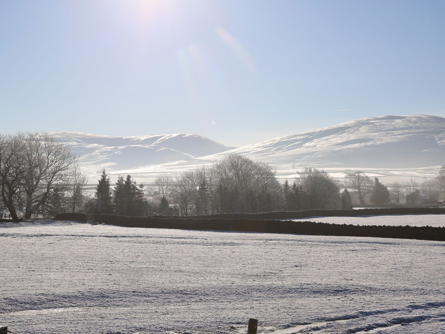 A snowy landscape with mountains in the background and a clear sky.