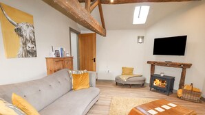 A living room with a grey sofa, wooden coffee table, and a fireplace. - The Hayloft (Holmfirth)