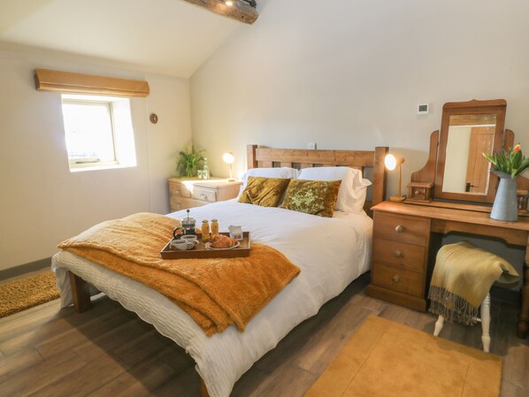 A bedroom with a bed, bedside table, dresser, and a window.