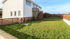 A modern house with a stone staircase leading to a wooden deck. - Windy Ridge (Holyhead)