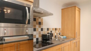 Une cuisine moderne avec des meubles en bois, un four à micro-ondes en acier inoxydable, une machine à café et une bouilloire.