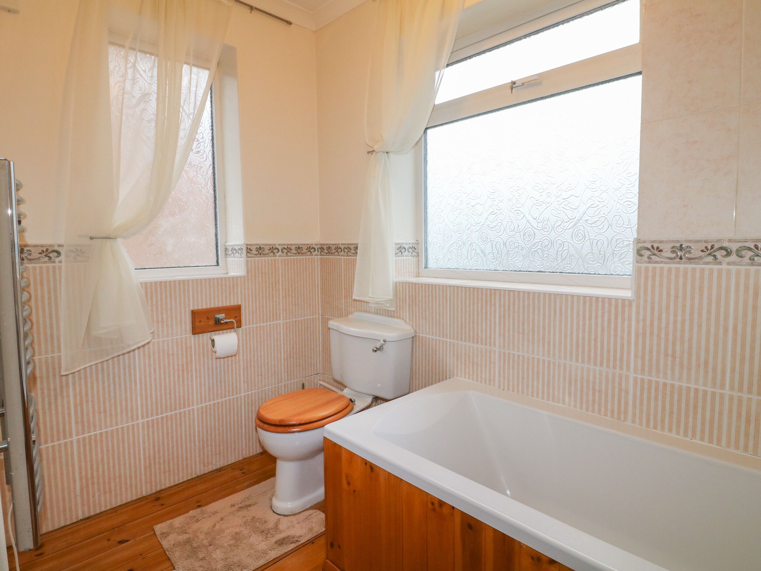 A bathroom with a toilet, a bathtub, and a window.