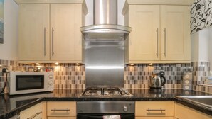 A modern kitchen with stainless steel appliances, wooden cabinets, and a tiled backsplash. - Helredale Retreat Whitby (Whitby)