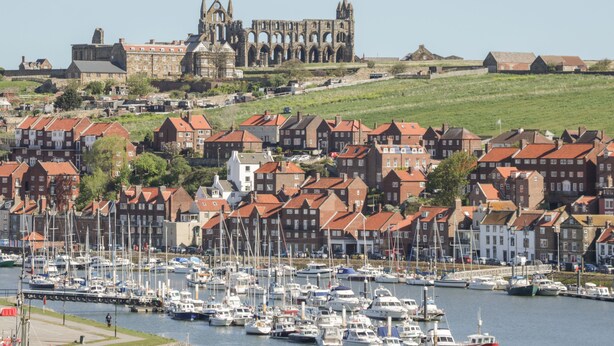 A coastal town with a historic cathedral in the background, a marina with numerous boats, and traditional red-roofed houses. - Helredale Retreat Whitby (Whitby)