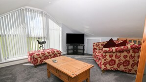 A spacious living room with a wooden coffee table, a sofa, and a television.