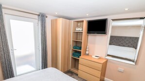 A hotel room with a bed, a TV mounted on the wall, a dresser, and a wardrobe.