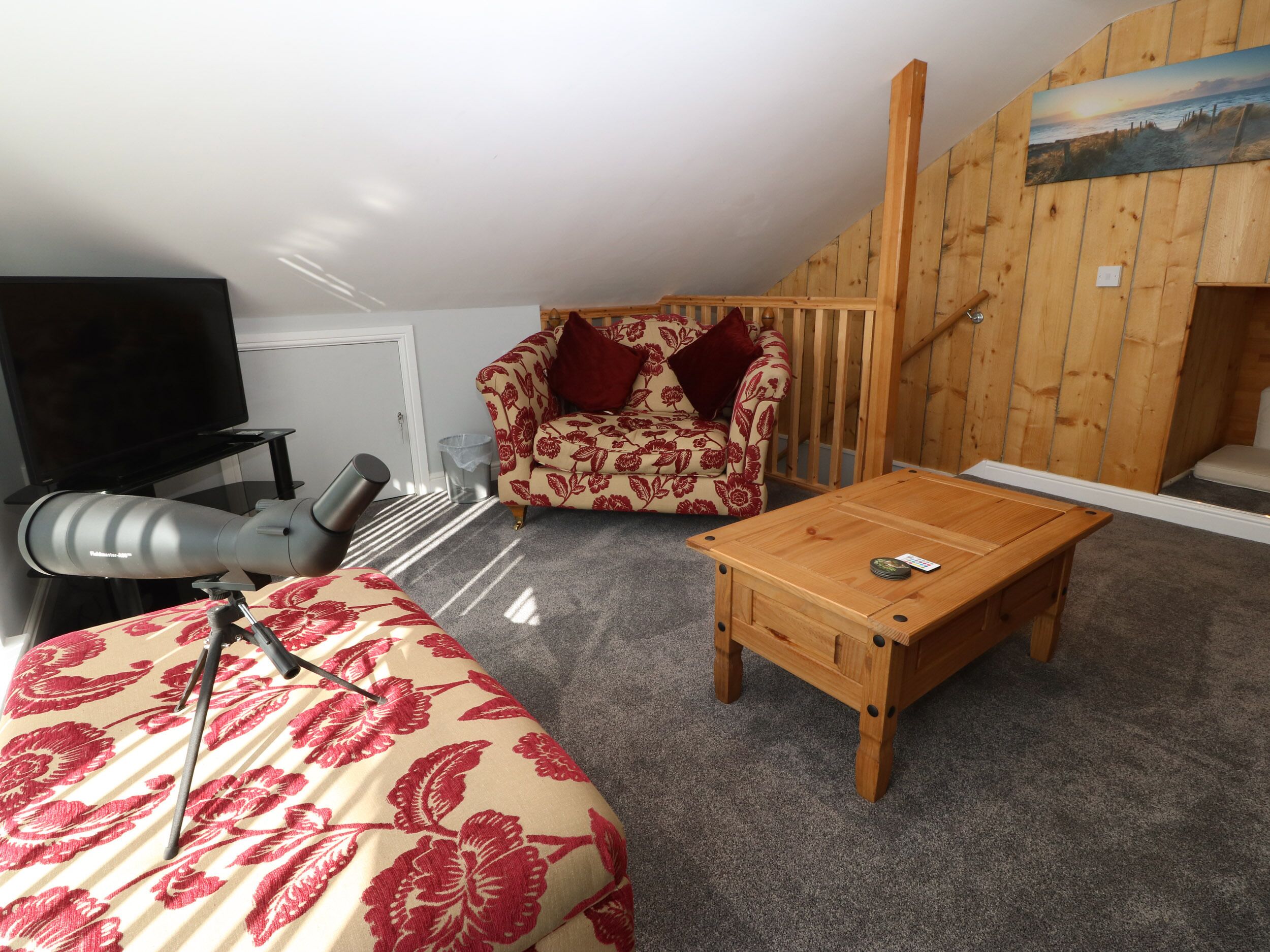 A cozy room with a sofa, a wooden coffee table, a telescope, and a painting on the wall.