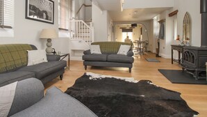 A spacious living room with a large black and white cowhide rug, grey sofas, and a dining area in the background.