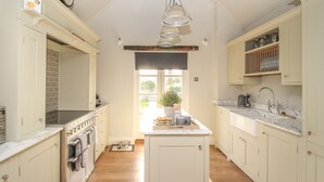 A kitchen with white cabinets, a stove, and a sink. There is a window with a view of greenery outside.