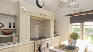 A kitchen with a microwave, oven, and a clock on the wall.