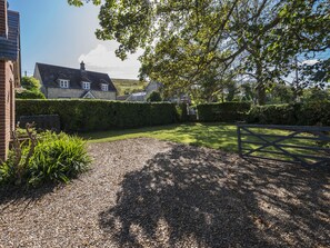A garden with a gravel path leading to a wooden gate, a stone wall, and a house with a pitched roof. - St Mary's Chapel (Wareham)
