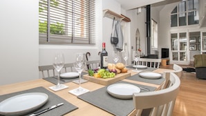A dining area with a table set for four, including wine glasses, plates, and a fruit platter.