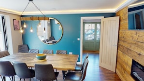 Uma sala de jantar com uma mesa de madeira, cadeiras pretas e um lustre.